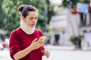 young woman with a personal injury wearing a neck brace outdoors